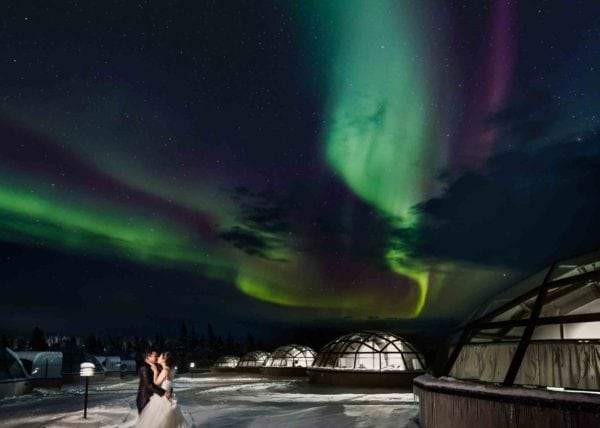 Aura lights for married couple in Iceland next to Igloos